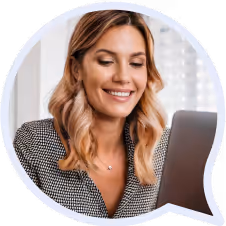 Smiling woman with light brown hair looking at a laptop screen.